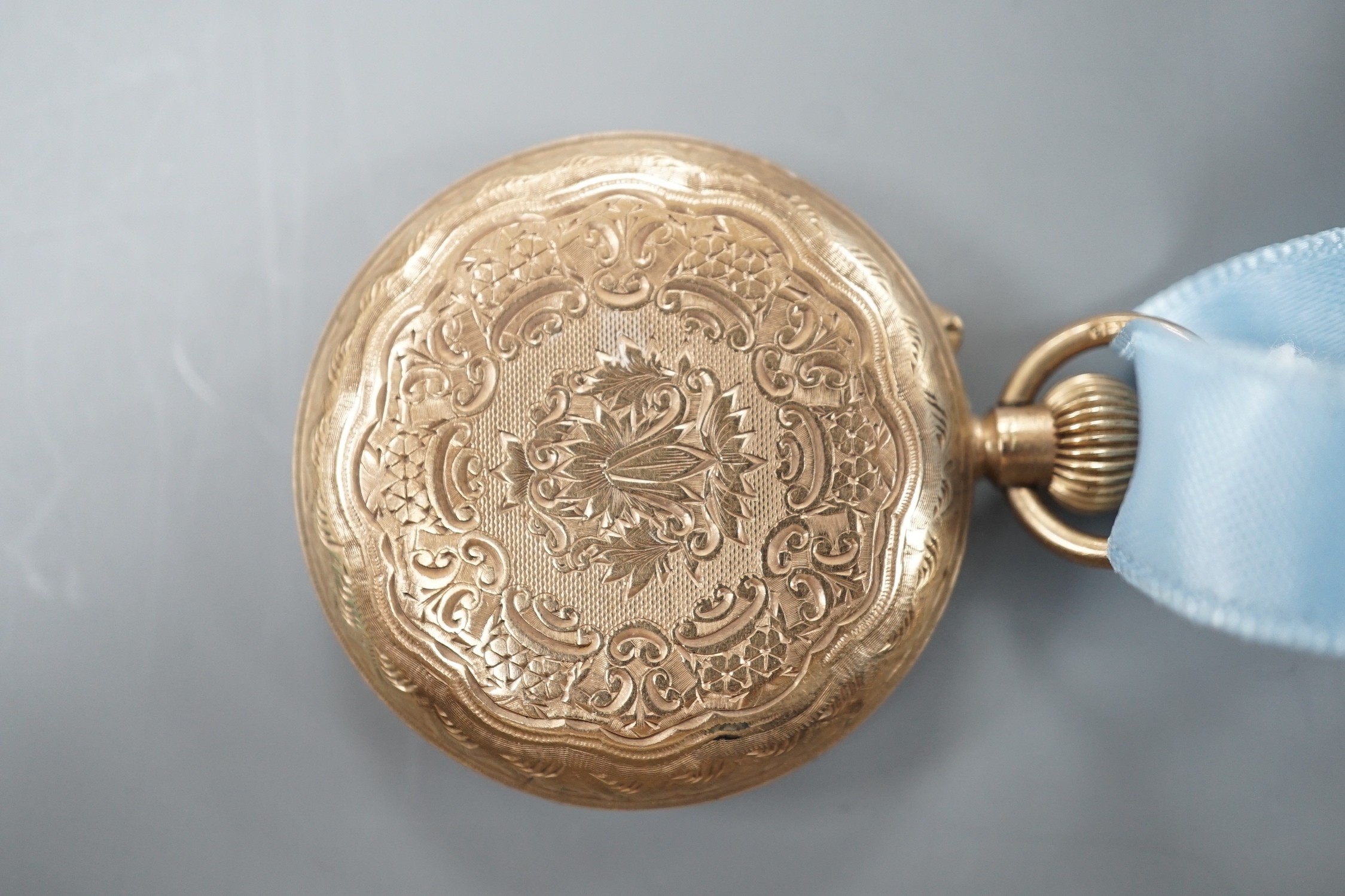 An early 20th century engraved 9ct gold hunter fob watch, with Roman dial, gross 36.7 grams, on a blue sash with yellow metal mounted hardstone fob.
